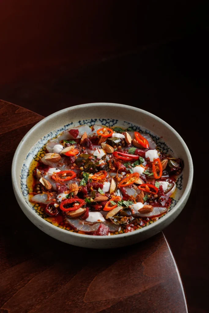 Cured sea bream with blood orange pachadi at Tanvi, an Indian restaurant in St George’s Bay Malta, garnished with almonds, chilli and herbs.